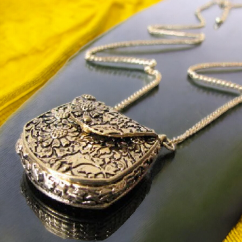 Image of a vintage carved bronze locket pendant necklace with a long chain.