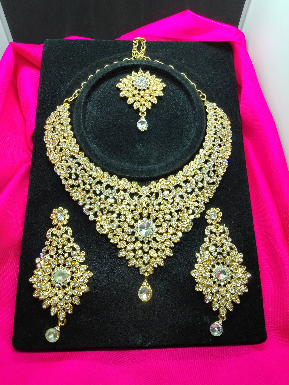 Bridal jewelry set featuring antique gold necklace, earrings, and tikka with dazzling white zirconia stones.